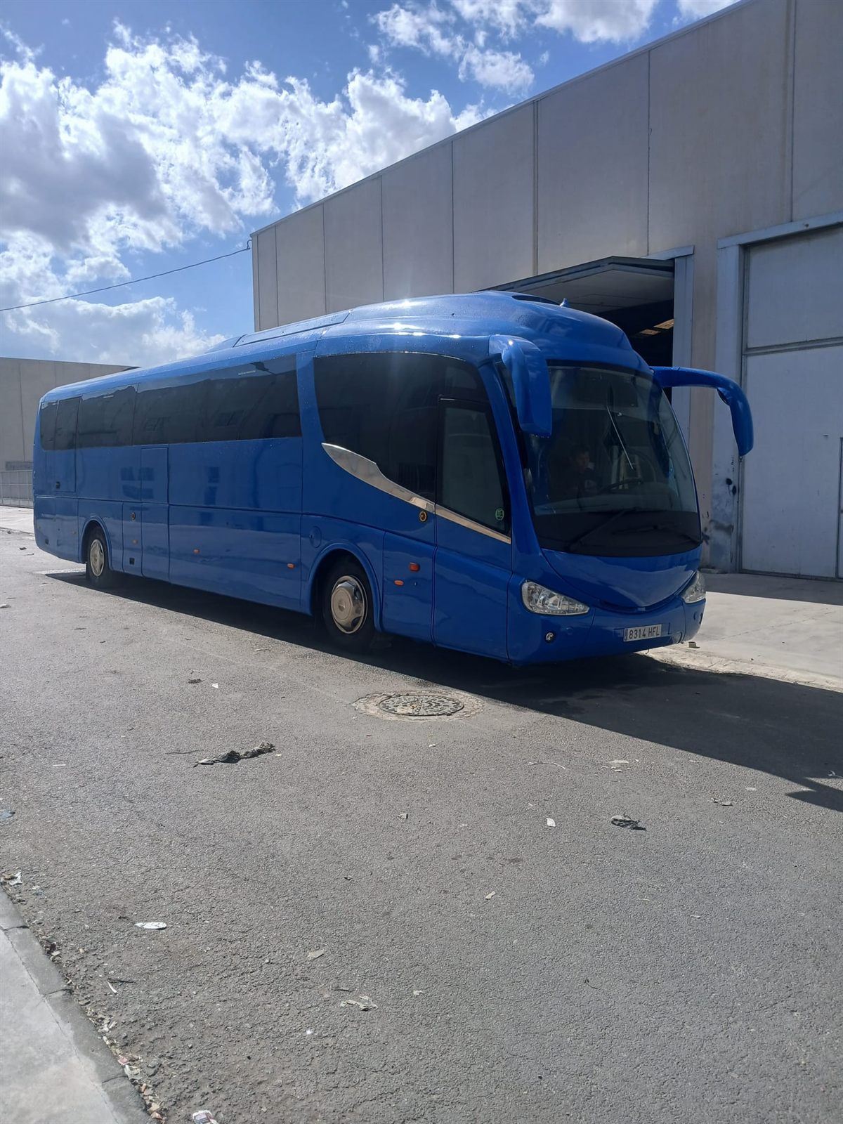 Autocar azul eléctrico junto a la nave